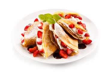 Crepes with strawberries and cream on white background 