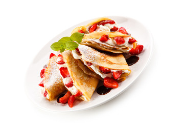 Crepes with strawberries and cream on white background 