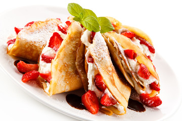 Crepes with strawberries and cream on white background 