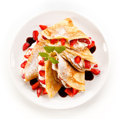 Crepes with strawberries and cream on white background 