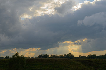 Naklejka na ściany i meble dark cloudy sky with clouds over a green field