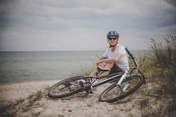 Woman resting after riding bike on the beach 