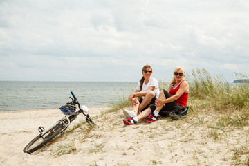 Women resting after riding bike on the beach 