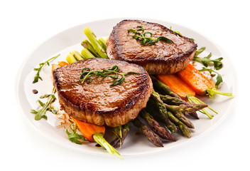Grilled beef steaks with asparagus and carrots on white background 