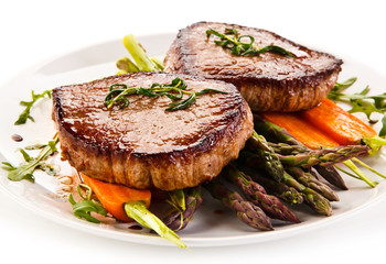 Grilled beef steaks with asparagus and carrots on white background 