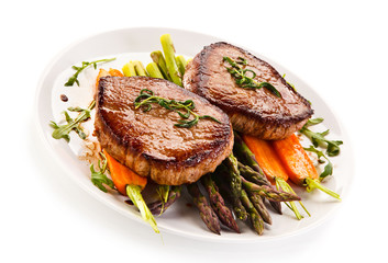 Grilled beef steaks with asparagus and carrots on white background 
