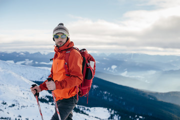 A handsome man wearing a bright sportswear with a backpack traveling in winter Carpathians mountain, Ukraine