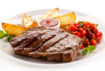 Grilled steak, baked potatoes and vegetable salad on white background 