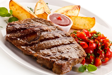 Grilled steak, baked potatoes and vegetable salad on white background 