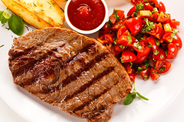 Grilled steak, baked potatoes and vegetable salad on white background 