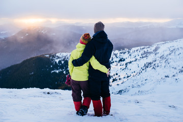 Loving couple in sportswear travels in the winter Carpathians mountain, Ukraine