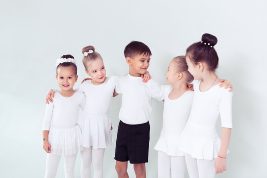 Cute Little Kids Dancers On White Background. Choreographed Dance By A Group Of Small Ballerinas Practicing At A Classical Ballet School
