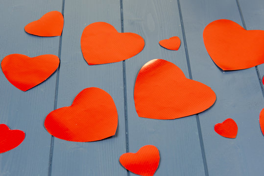 Multiple red hearts on a blue wooden background 