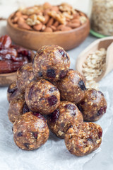 Healthy energy balls with cranberries, nuts, dates and rolled oats on parchment, vertical