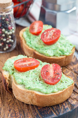 Open sandwiches with mashed avocado and cherry tomatoes, sprinkled with black pepper, vertical