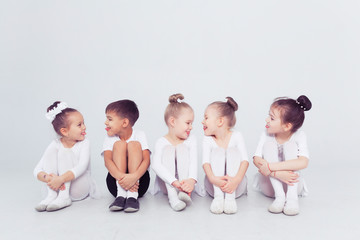 Cute little kids dancers on white background. Choreographed dance by a group of small ballerinas practicing at a classical ballet school