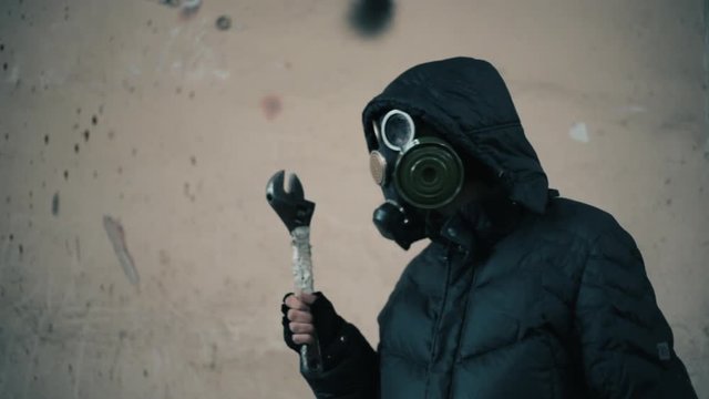 Man in gas mask, stalker or maniac with wrench, apocalipse survival concept