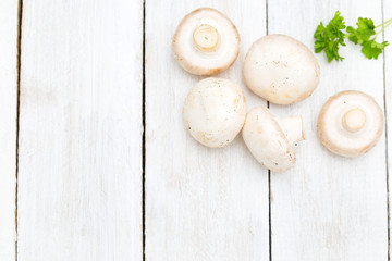 Fresh organic champignon mushrooms on white wood background. Copy space