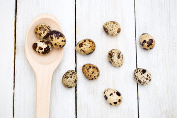 Group of quail eggs and a wooden spoon on a wooden background. Flat lay