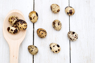 Quail eggs and a wooden spoon on a wooden background. Flat lay