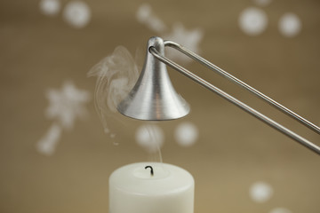 White candle, freshly extinguished. Silver candle snuffer. Christmas atmosphere.
