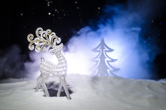Christmas garlands in the tree form and figure of a deer on the street during a snowfall.