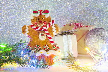 Gingerbread cookie and small gift box on bright festive Christmas background