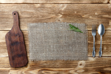 Cooking background concept. Vintage cutting board, sackcloth and cutlery. Top view with copy space.