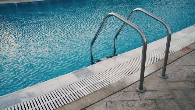 Ladder to the pool. Water ripples. Overflow swimming pool