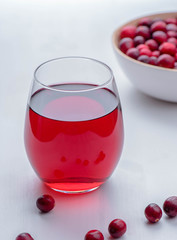 Freshly squeezed lingonberry juice with berries on the white wood table. 