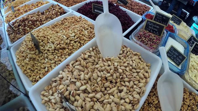 4K pan shot of stand with variety of nuts and dried fruits at farmer market place in Normandy, France. Natural healthy food and abundance concept