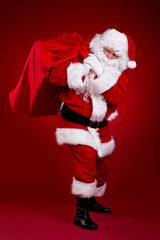 Santa Claus carrying big bag , isolated on red  background