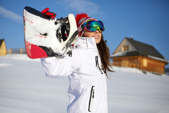 Sporty female holds snowboard in mountains