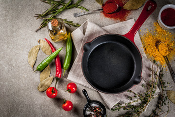 Grey stone culinary background with empty black pan and selection of spices and seasonings, top view copy space