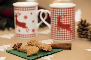 Christmas composition – mugs with deer motive, cookies, cinnamon sticks, anise, pinecones and plaid blanket.