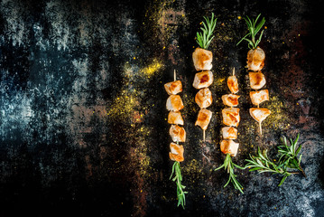 Grill, barbecue meat. Chicken skewers with rosemary. On a black rusty metallic background, copy space top view