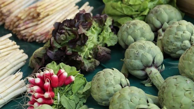 Pan video of vegetables stand with fresh white asparagus bunches, radish and artichokes at the farmers market place in Dieppe, France. Regional cuisine, natural healthy food and abundance concept
