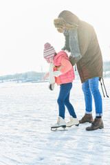 Kind macht erste Schritte beim Schlittschuh laufen
