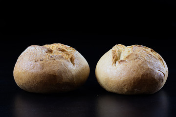 Fresh bread, rolls on black salts. Black background