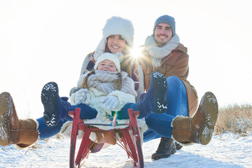 Glückliche Familie beim rodeln im Winter