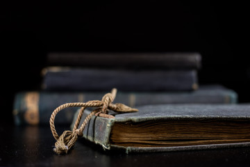 An old book lying on a black table. In the background a pile of old chunks. Black table,