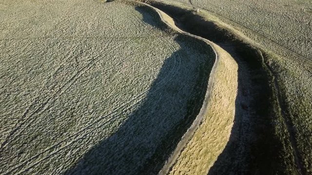 Aerial view over an ancient Motte and Bailey relief on a frozen winter morning at dawn in Oxfordshire England