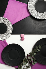 Fancy plates on black and white background. Creative restaurant table setting with flowers and...