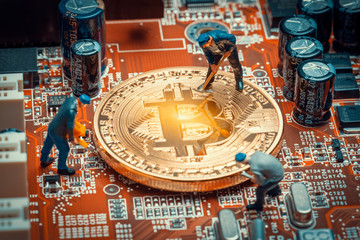 macro miner figurines working on a bitcoin on computer motherboard
