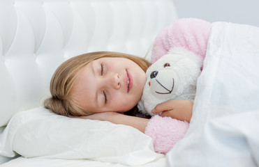 Obraz na płótnie Canvas Sleeping girl hugging a toy bear
