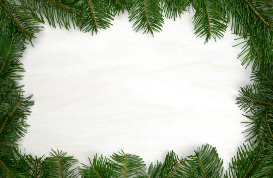 einfacher Rahmen aus Tannenzweigen und wei&szlig;em, hellem Hintergrund aus Holz