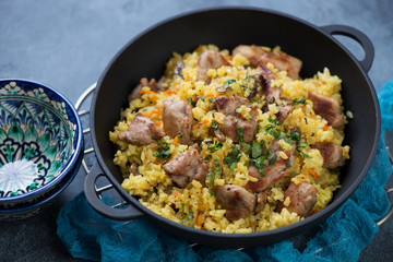 Close-up of a cast-iron pan with pilaf, selective focus, studio shot
