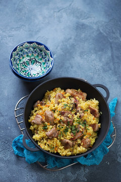 Pilaf served in a cast-iron pan on a blue stone background, high angle view with copyspace