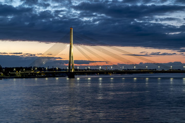 Fototapeta na wymiar View of the cable-stayed bridge and the embankment of the river Daugava in Riga at sunset.