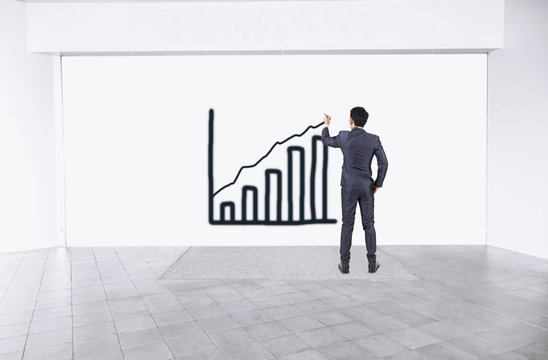 Businessman drawind growth chart on empty interior mock up